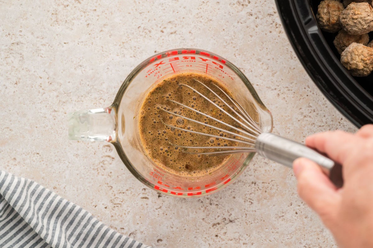 Whisking together water, ranch, gravy packet, and pepperoncini juice in a measuring cup.