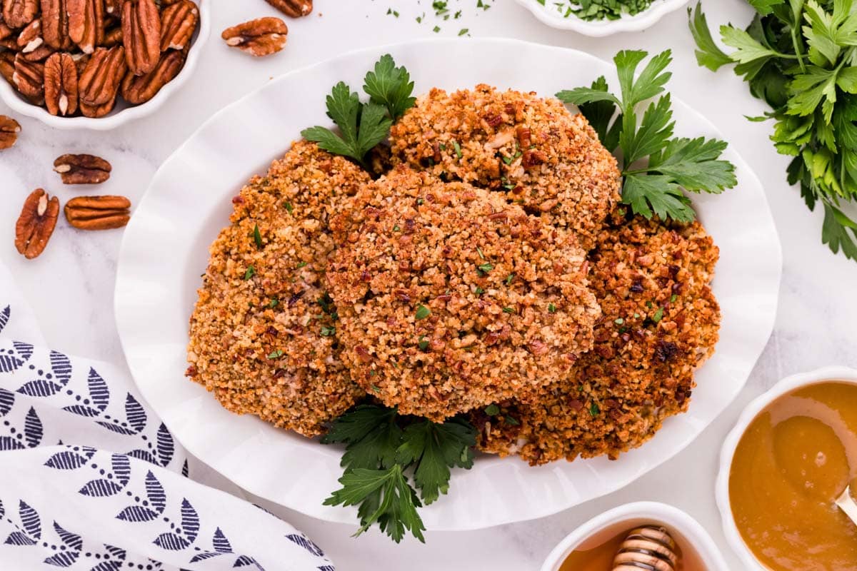 Pecan crusted chicken served on a serving platter with herbs.