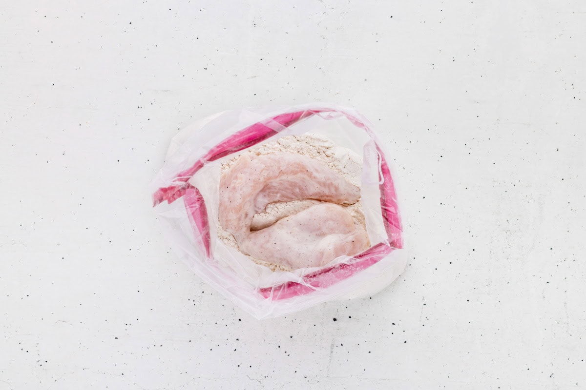 Marinated chicken added to the breading mixture in a ziplock bag.
