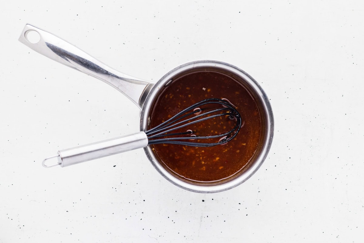 Whisking together the thickened sweet chili sauce in a saucepan.