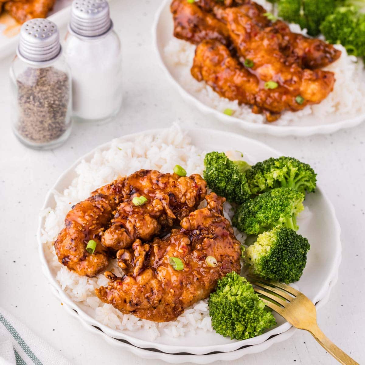 Sweet chili chicken fingers served on a plate with rice and broccoli.