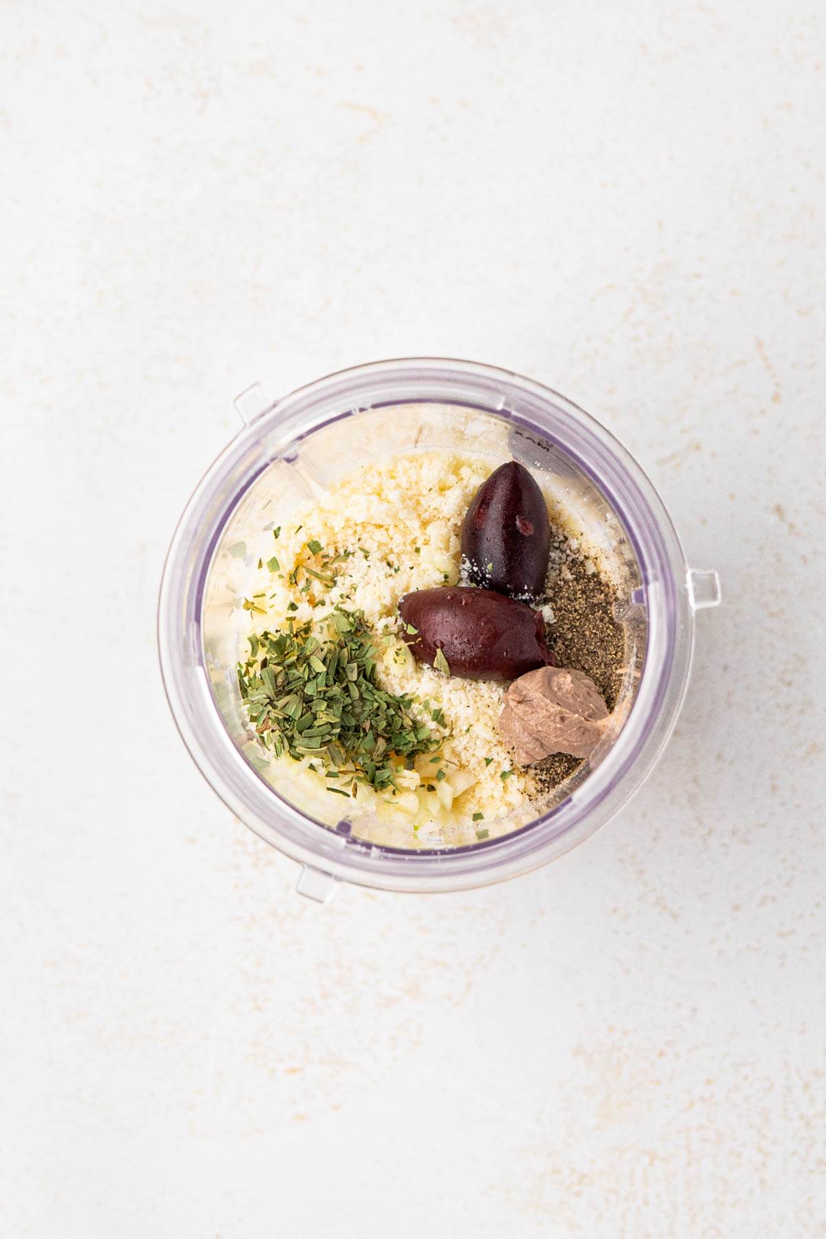 An overhead view of the blender cup with ingredients for the creamy parmesan salad dressing.