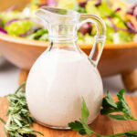 A glass salad dressing bottle filled with homemade creamy parmesan dressing (carrabba's copycat).