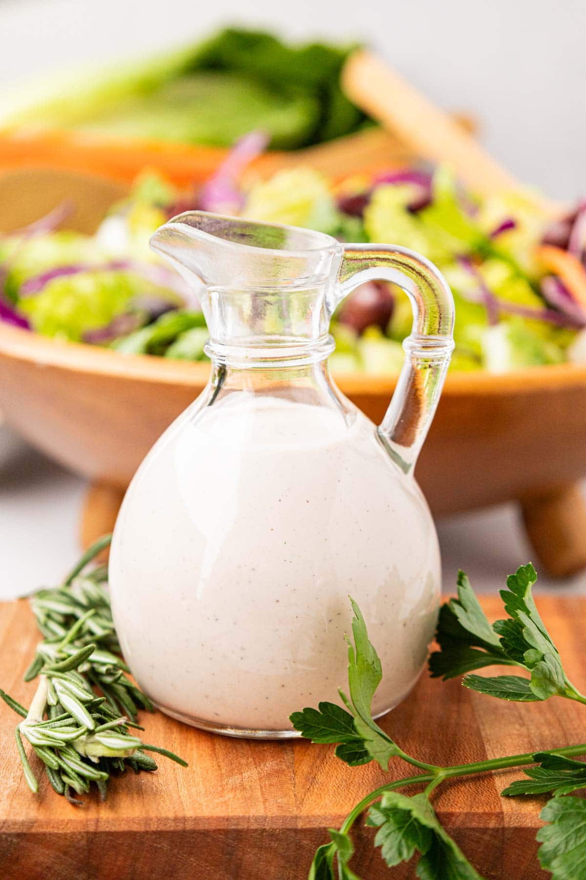 A glass salad dressing bottle filled with homemade creamy parmesan dressing.