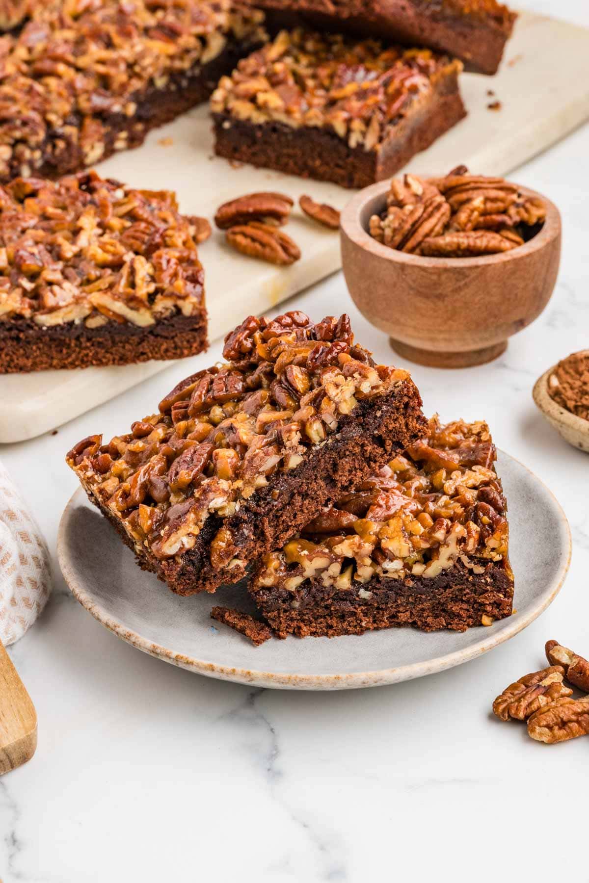 Two pecan pie brownies leaning on each other on a plate.