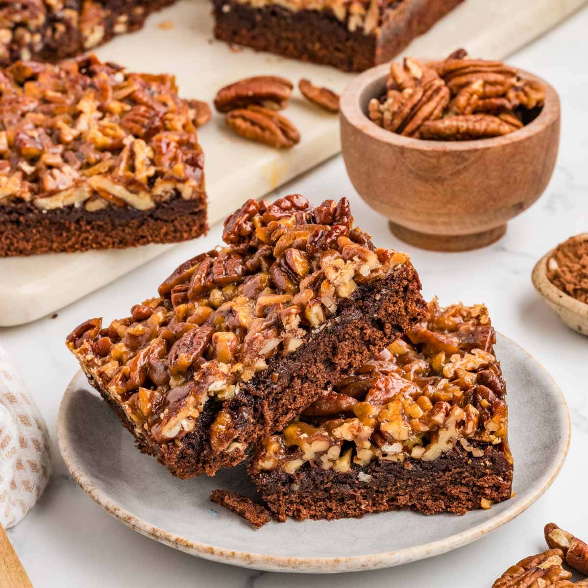 Two pecan pie brownies leaning on each other on a plate.