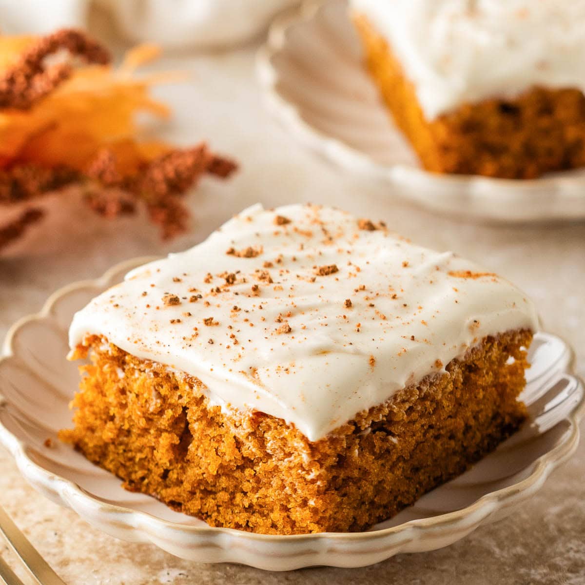 Side view of a pumpkin bar with cream cheese frosting on a plate.