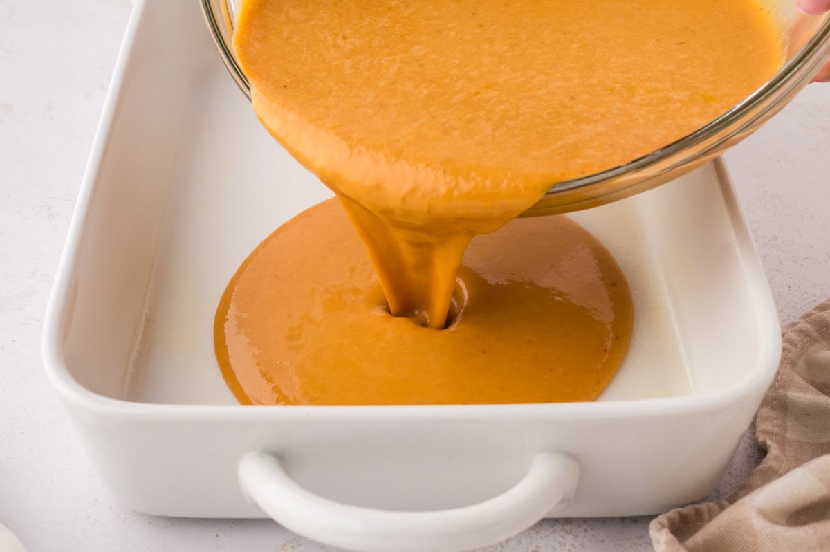 Pouring the pumpkin custard from the bowl to the 9 x 13 dish.
