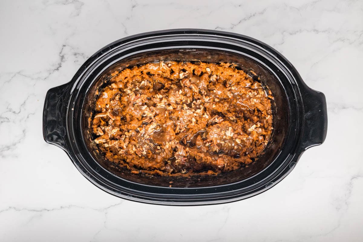 Pecan mixture placed on top of the mashed sweet potatoes in a slow cooker.