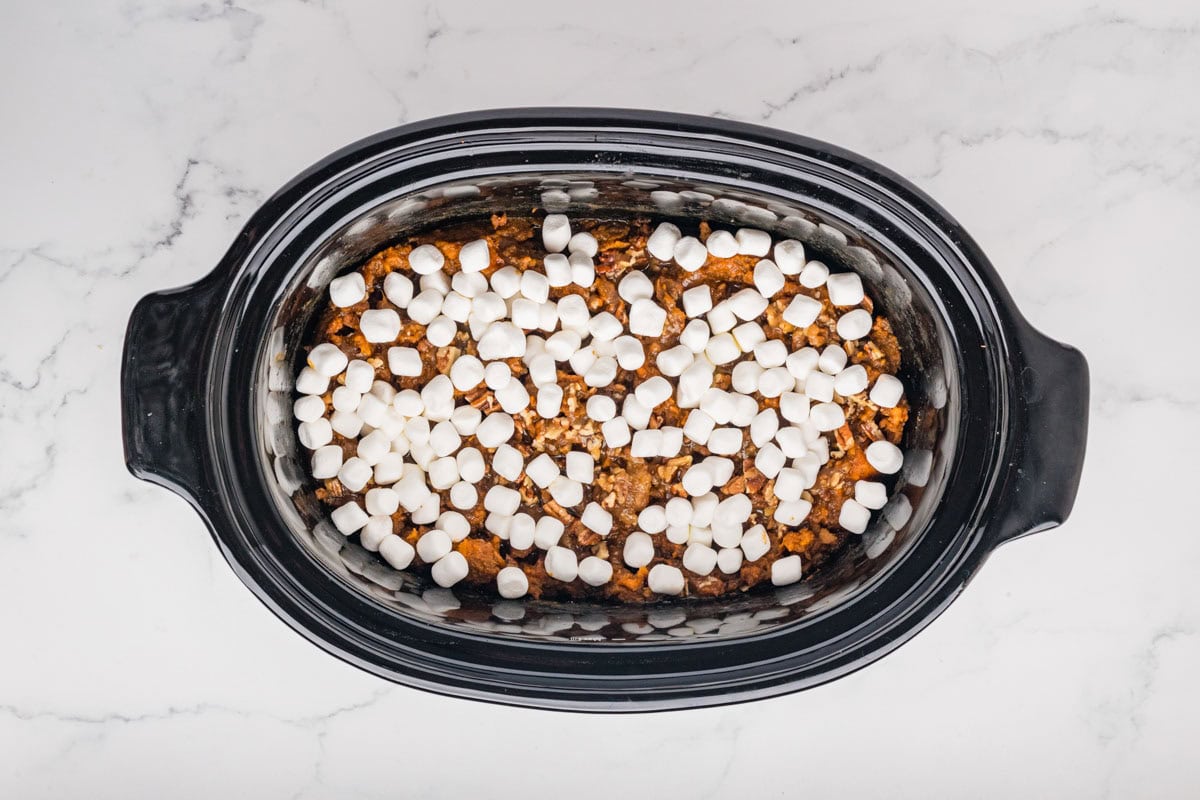 Mini marshmallows placed on top of the sweet potato casserole in a slow cooker.