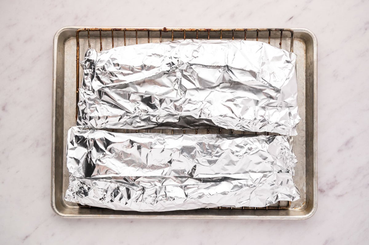 Both sets of ribs tightly wrapped in foil on a baking tray to transport to the smoker.