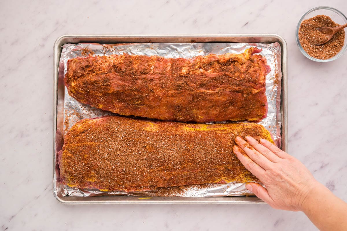 Rubbing the rib rub seasoning on the ribs by hand.