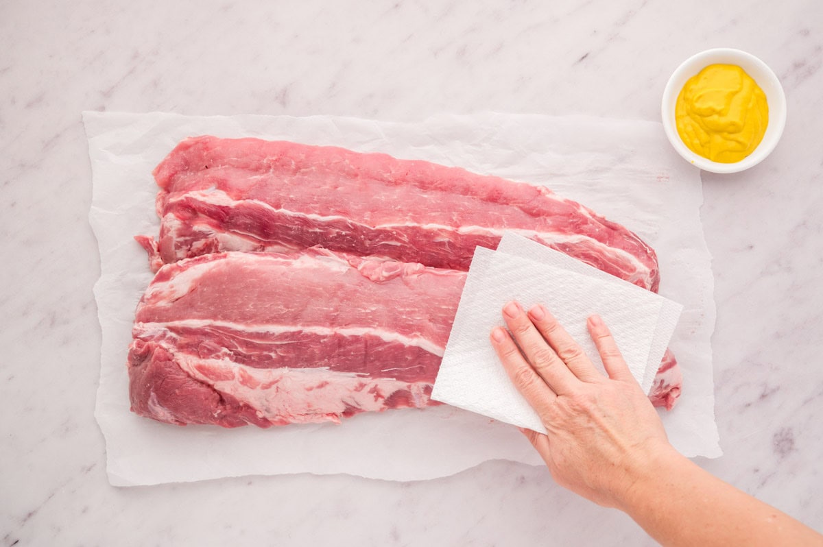 Patting baby back ribs dry with a paper towel.