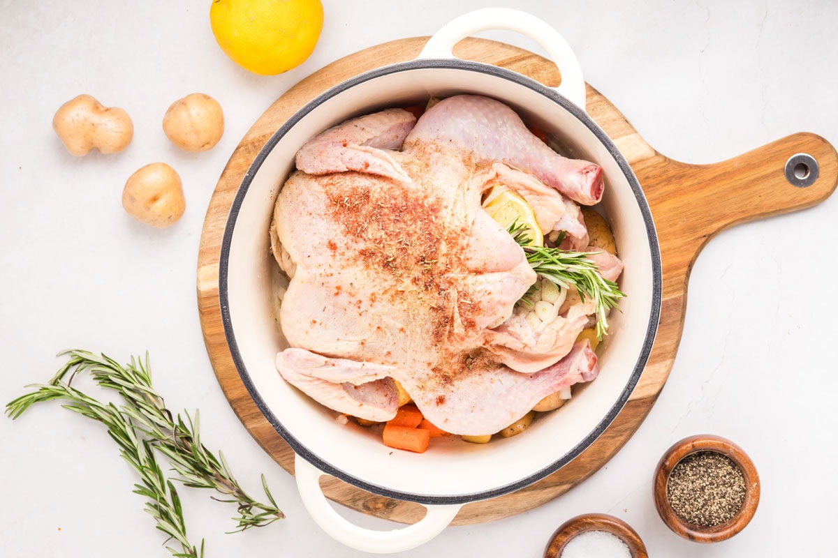 Seasoning on top of the whole chicken in a Dutch oven.
