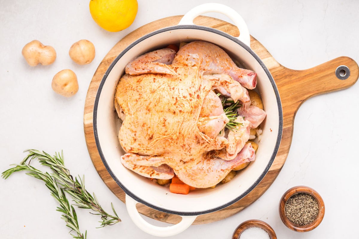 Seasoning spread on top of the whole chicken in a Dutch oven.