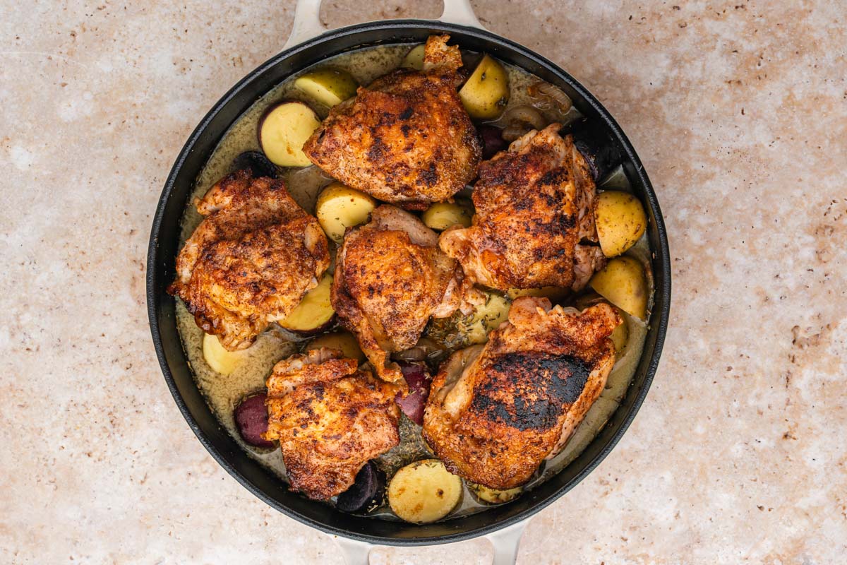 Seared chicken placed into the skillet with broth and Dijon mixture along with the onions and potatoes.