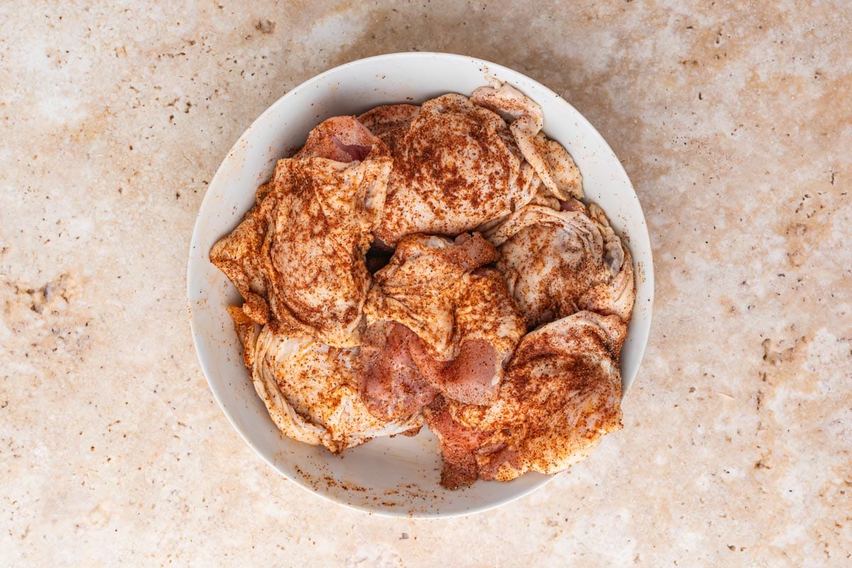 Chicken thighs with dry rub spread on them.