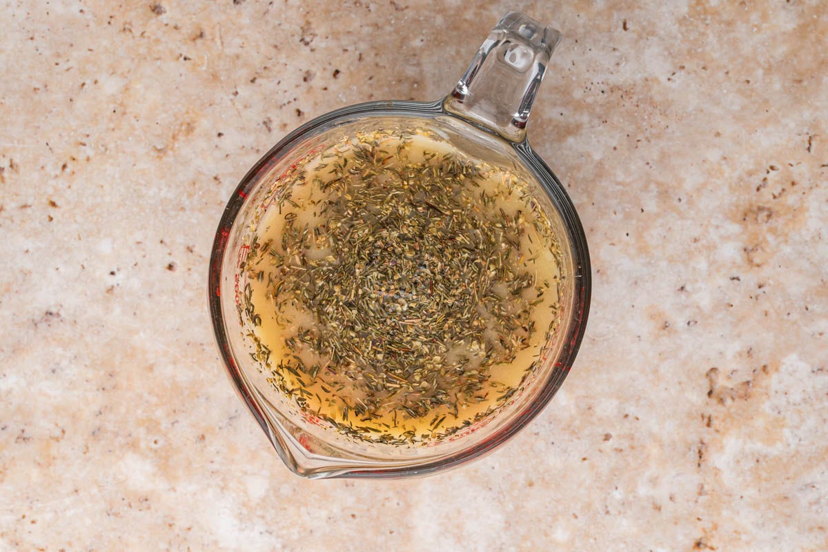 Chicken broth mixed with spices and Dijon mustard in a measuring cup.