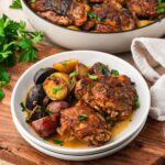 Maple dijon chicken thighs served on a plate with potatoes.
