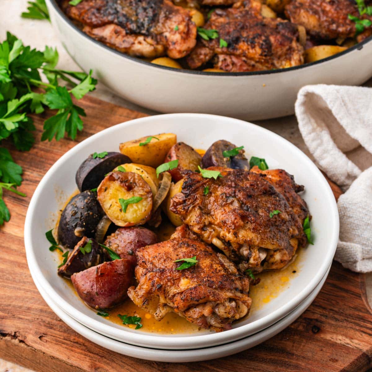 Maple dijon chicken thighs served on a plate with potatoes.
